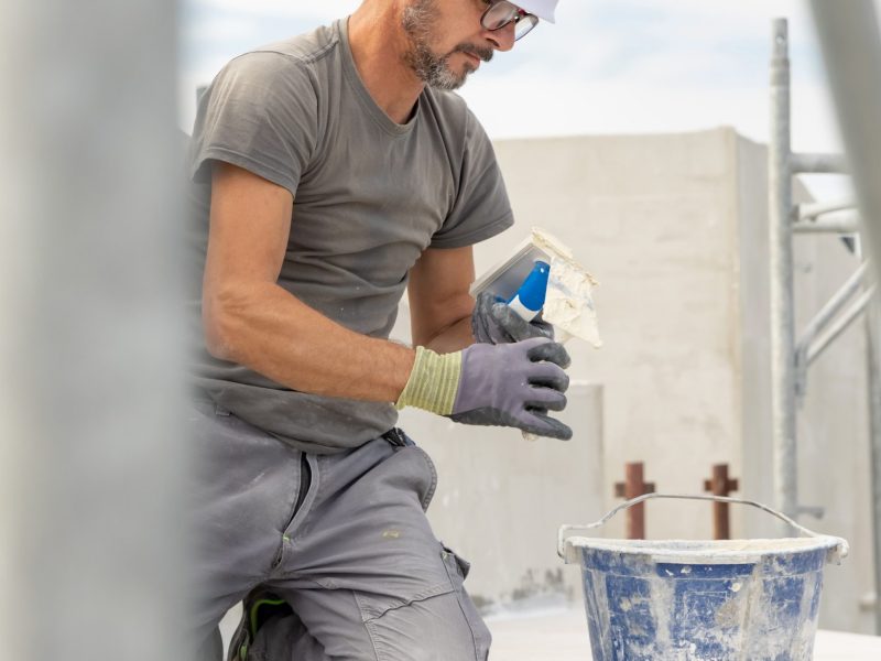 craftsman-in-grey-work-clothes-puts-grout-on-a-flo-2025-03-17-20-57-05-utc